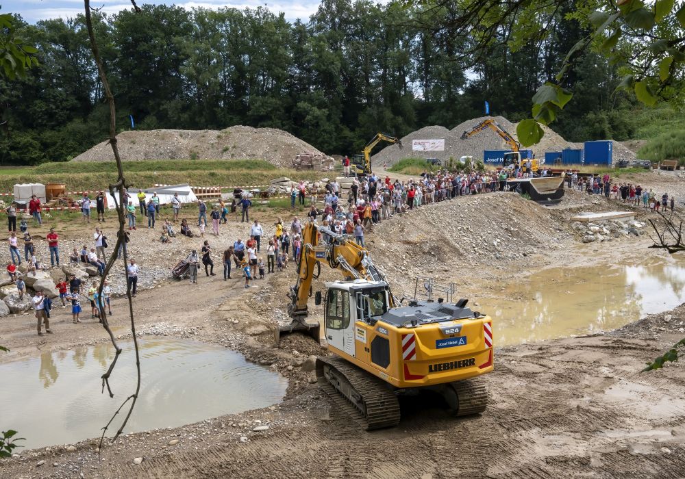 Blick auf die Baustelle im Fluss mit vielen Menschen