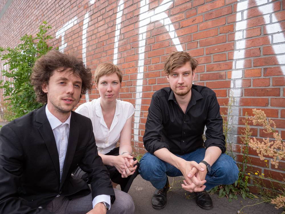 Barock Trio in der Hocke vor einer Backsteinwand