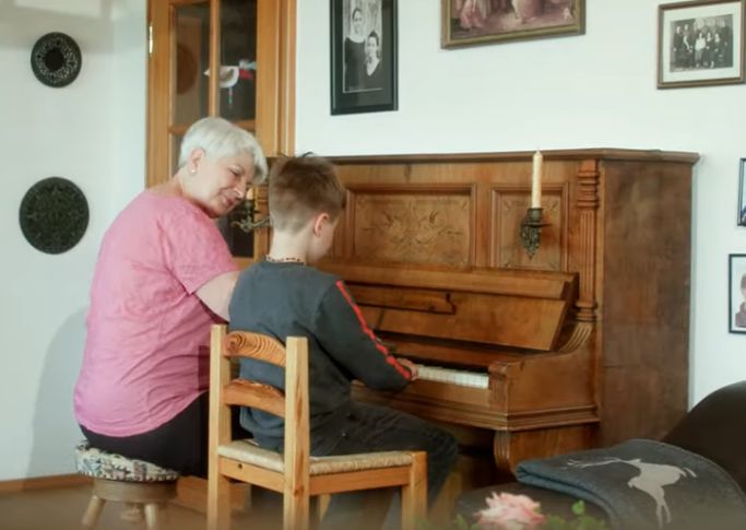 Ältere Frau lehrt einem Kind am Klavier