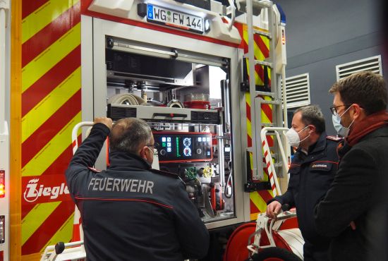 Drei Männer schauen ein Feuerwehrauto an