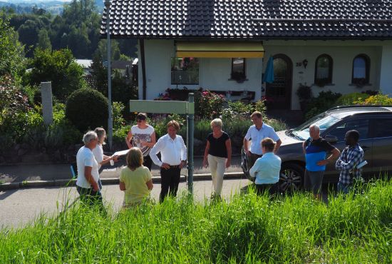 Menschen stehen vor einem Haus und sprechen miteinander
