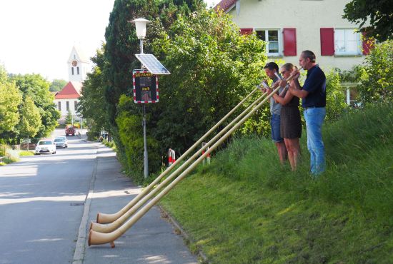 Zwei Männer und eine  Frau spielen Alphorn.