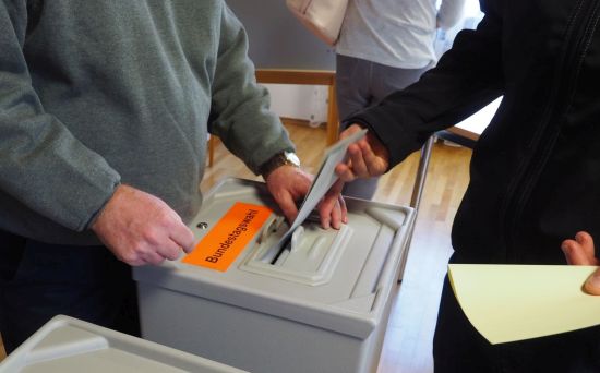 Wahlurne für den Bundestag, ein Mann steckt einen Umschlag hinein
