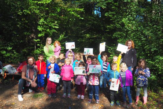 Kinder und Erzieherinnen mit gemalten Kinderbildern in der Hand