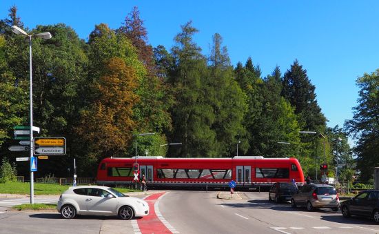 Bahnübergang mit Zug, Autos warten.
