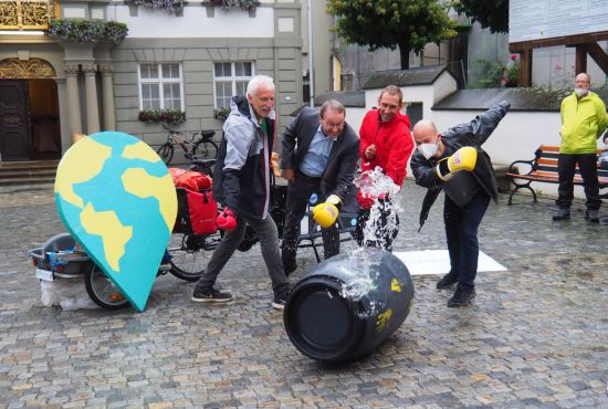 Vier Männer werfen eine Tonne um