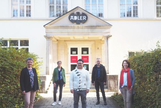 Fünf Personen vor einem großen Haus