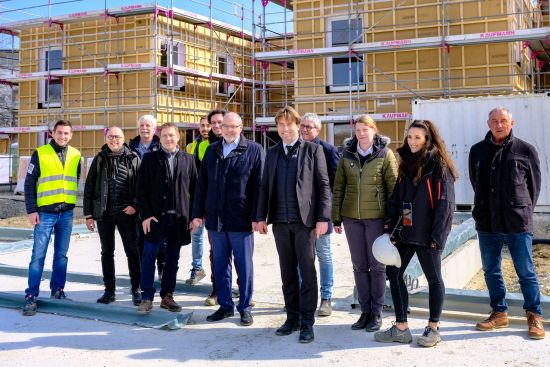 Männer und Frauen vor einer Wohnungsbaustelle