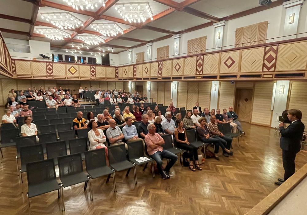 Menschen sitzen in den Zuschauerreihen in der Stadthalle