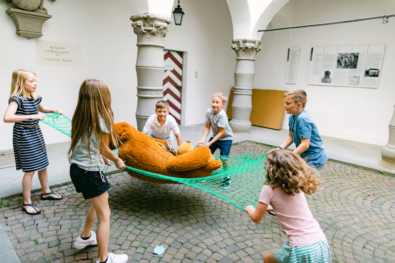 Kinderspielen mit einem großen Bär in einem Netz