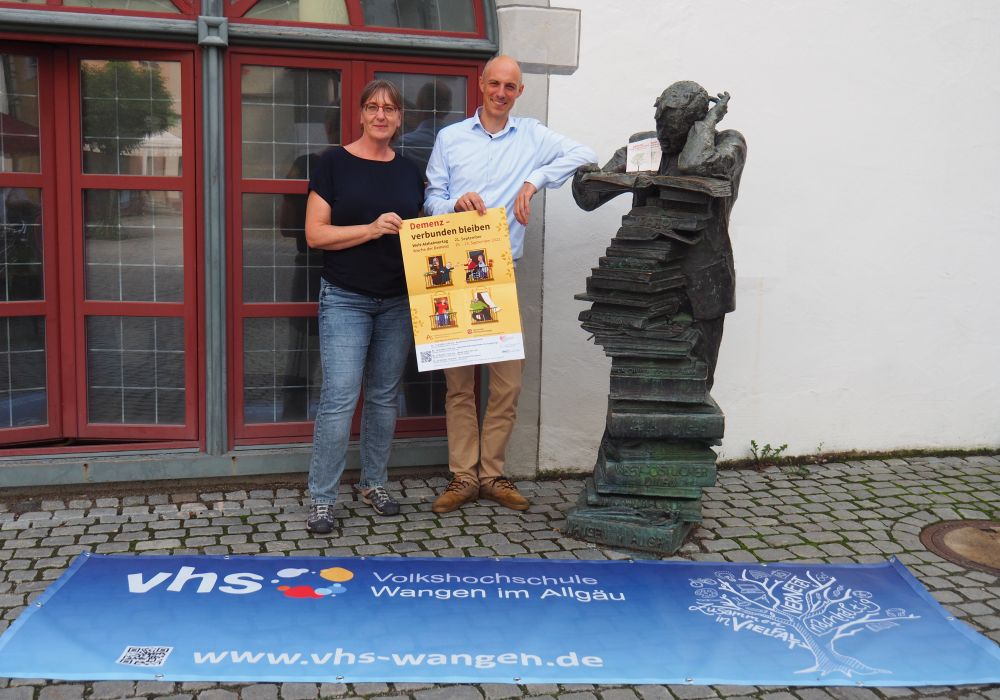 Ein Mann und eine  Frau zeigen vor der Bücherei das Plakat der Woche der Demenz