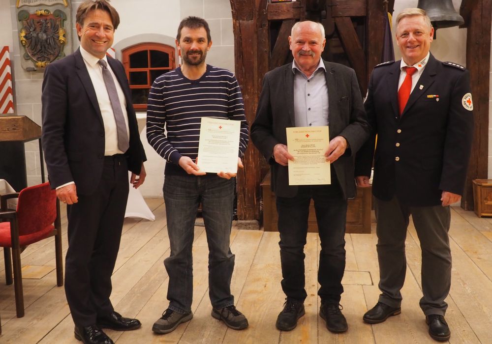 Vier Männer, zwei mit Urkunden