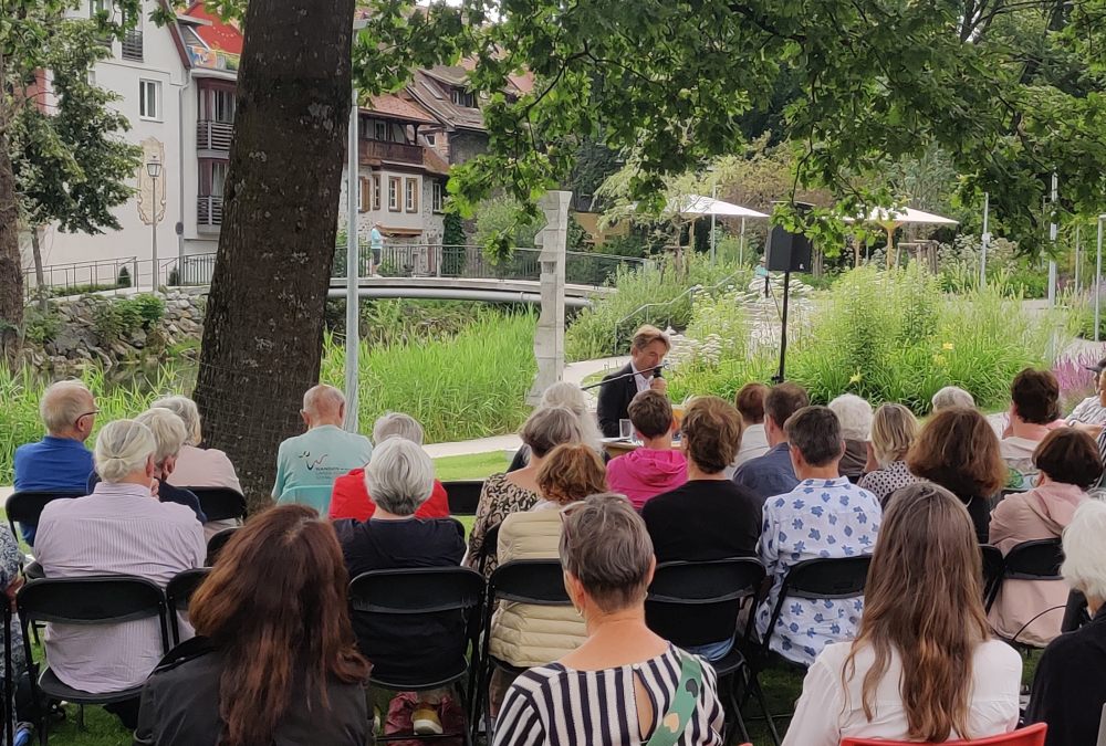 OB Michael Lang liest vor einer Gruppe Menschen im Stadtgarten 2024
