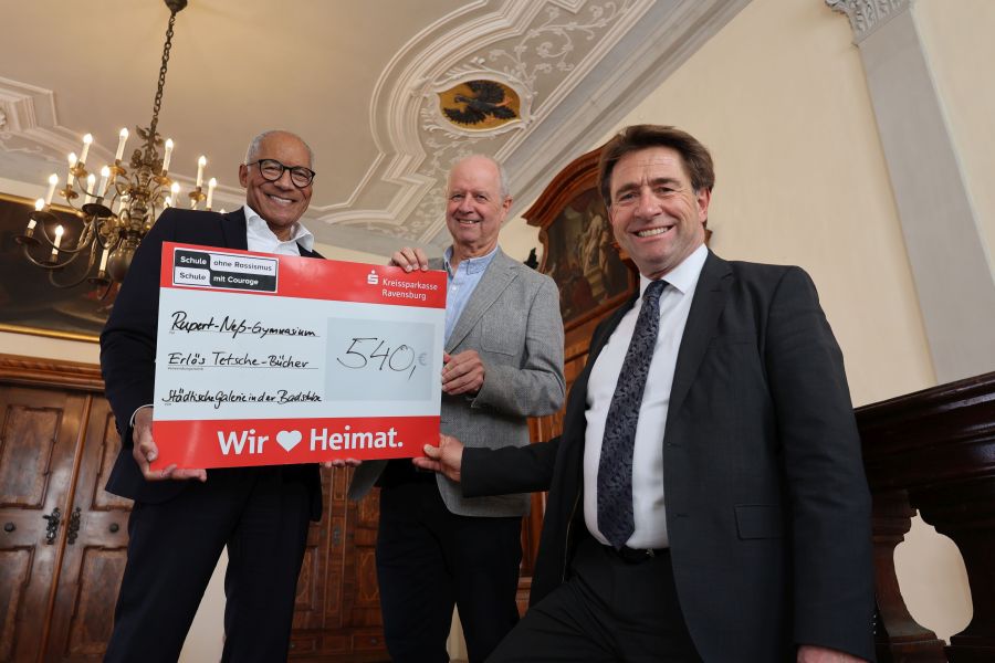 Drei Männer stehen auf einer Treppe und halten einen Scheck mit dem Betrag 540 Euro in die Kamera.