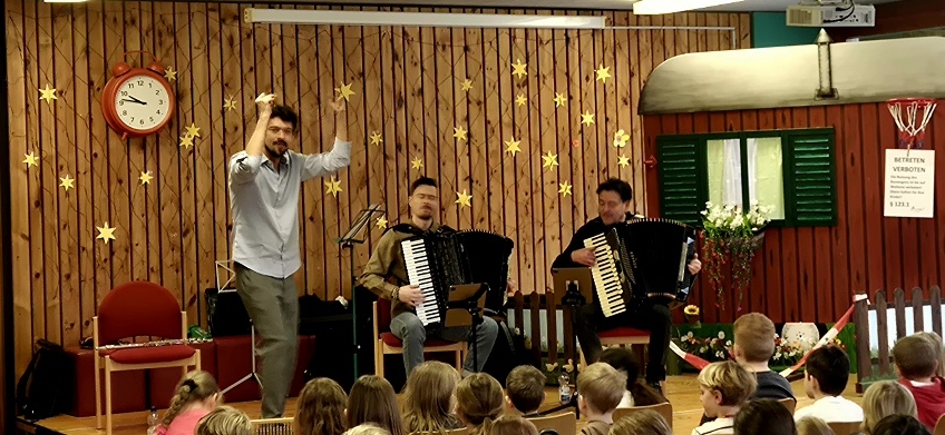 Drei Musiker und Schulkinder.