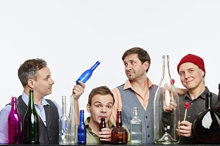 Die Bandmitglieder von GlasBlasSing mit leeren Flaschen im Vordergrund Bild