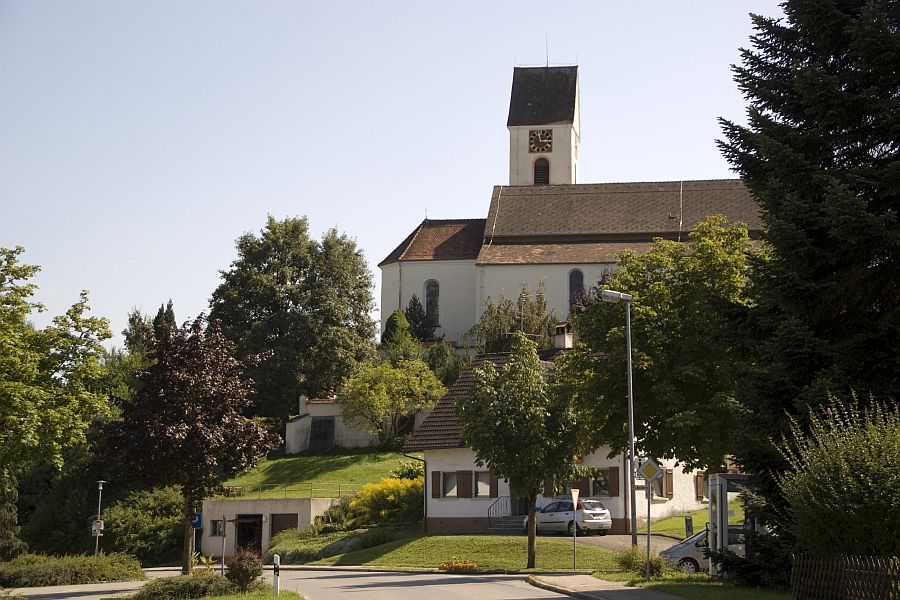 Blick auf die Kirche in Leupolz, die umgeben mit verschiedenen Bäumen ist