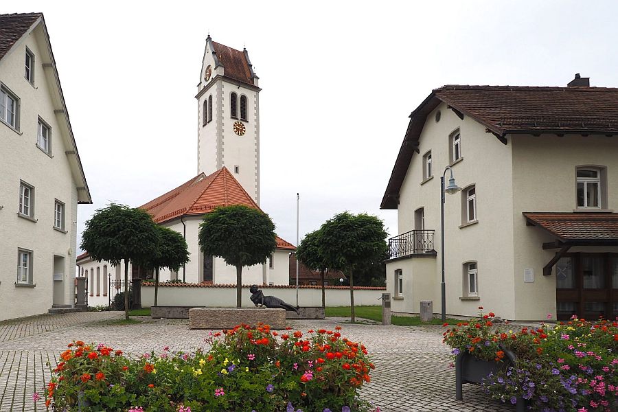 Dorfplatz in Niederwangen mit Brunnen und der Kirche im Hintergrund