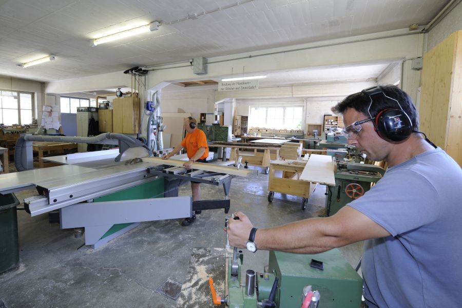 Zwei Mitarbeiter des Bauhofs arbeiten in einer Werkstatt an Holzbearbeitungsmaschinen Bild