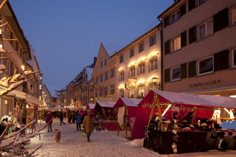 Weihnachtsmarkt mit schneebedeckten Ständen und stimmungsvoller Beleuchtung