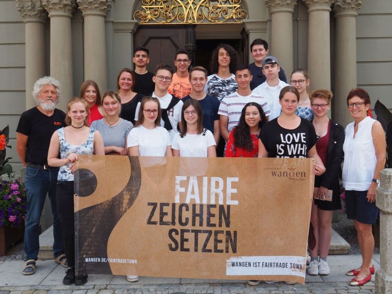 Eine Gruppe von Menschen hat sich mit einem Fair-Trade-Town-Transparent auf der Rathaustreppe zum Fototermin aufgestellt