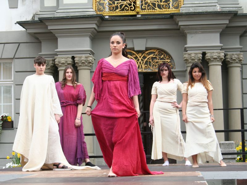 Modenschau vor dem Rathaus, fünf Models führen weiße und rote lange Kleider vor