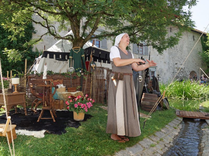 Mittelaltermarkt: eine mittelalterliche gekleidete Frau erklärt das Leben im Mittelalter