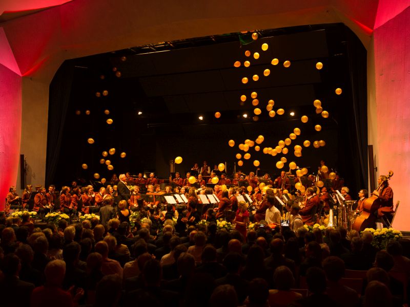 Festsaal Waldorfschule: Goldene Luftballons schweben auf die Stadtkapelle auf der Bühne herab