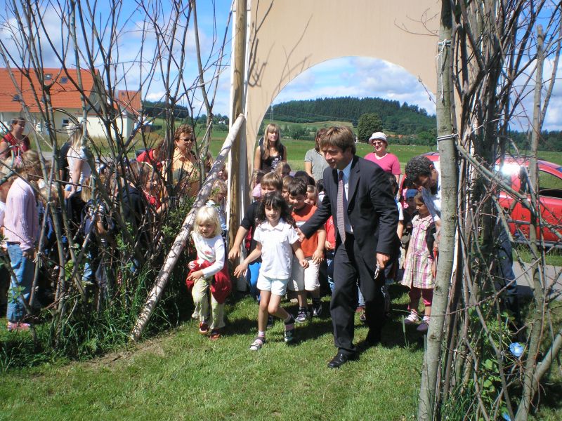 Oberbürgermeister Michael Lang betritt mit einer Gruppe von Kindern und Erwachsenen das neue Weidenlabyrinth
