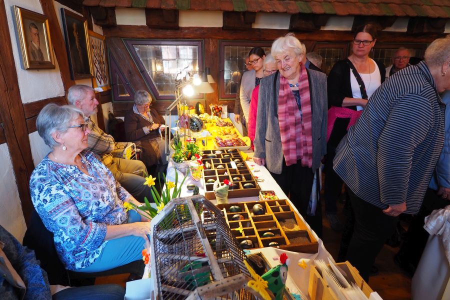 Marktbesucherinnen und -besucher betrachten die künstlerisch gestalteten Ostereier an den Verkaufsständen Bild