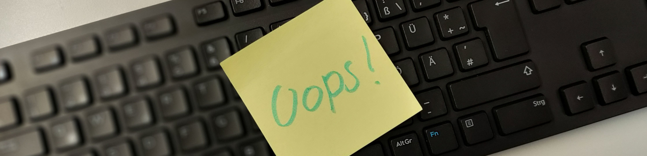 Ein Post-It mit der Aufschrift "Oops" auf einer Tastatur.