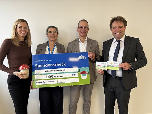 Vier Personen halten einen symbolischen Scheck.