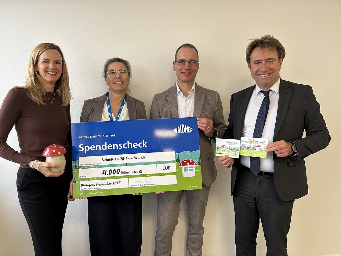 Vier Personen halten einen symbolischen Scheck.