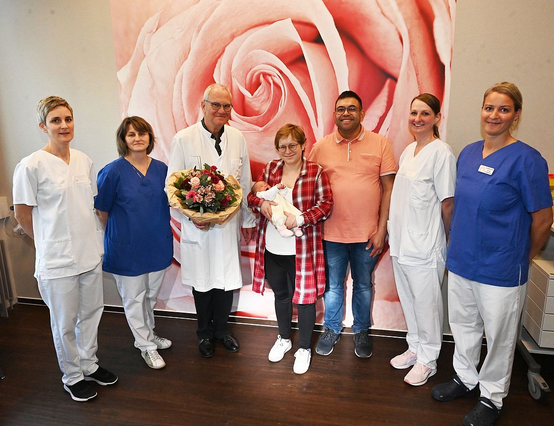 Eltern von Emma mit dem Baby, Chefarzt und vier weiteren Klinikmitarbeitenden