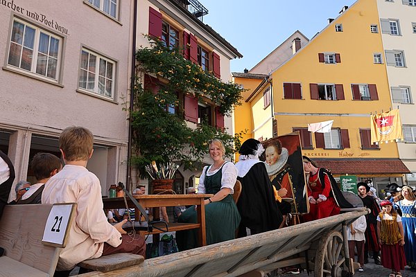 Ein Wangen in einem Umzug, mit Menschen in Kleidung aus der Renaissance-Zeit.