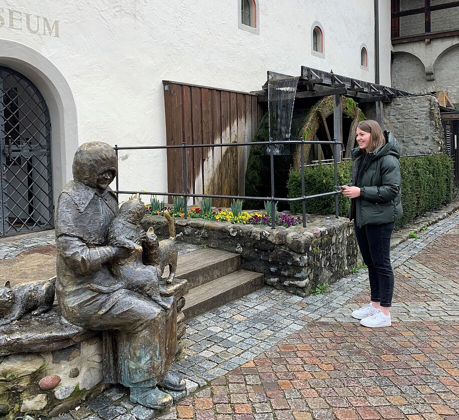 Junge Frau hört einer App vor dem Stadtmuseum zu
