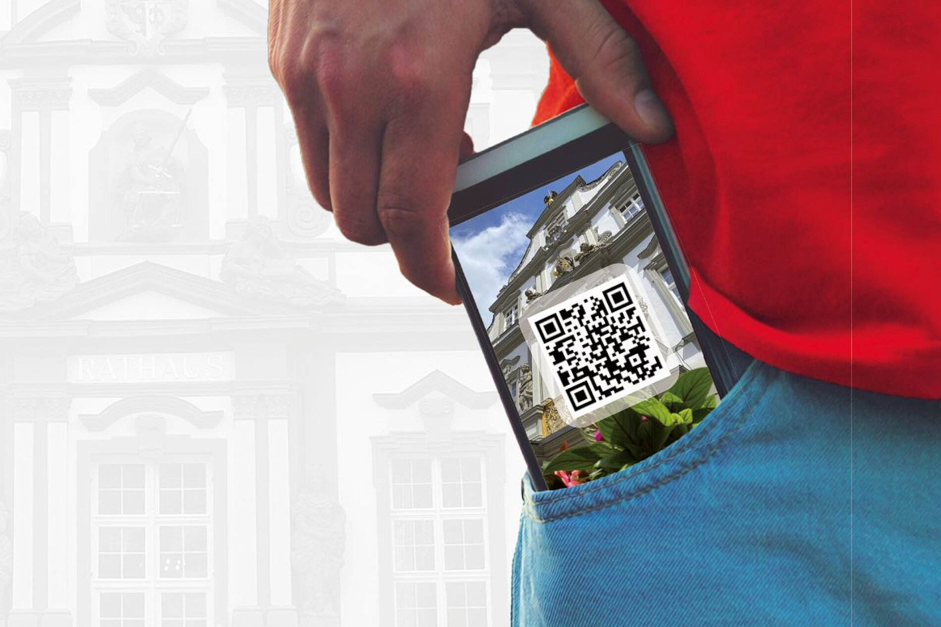 Ein Smartphone steckt in der Tasche einer Person, auf dem Bildschirm ist ein QR-Code und ein Bild eines Gebäudes zu sehen. Der Hintergrund zeigt verschwommen eine architektonische Struktur.