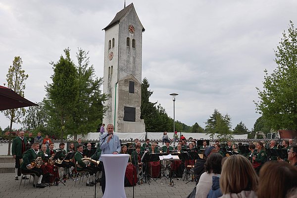 Ein MAnn spricht vor vielen Menschen. Die Musikkapelle Schwarzenbach sitzt hinter ihm