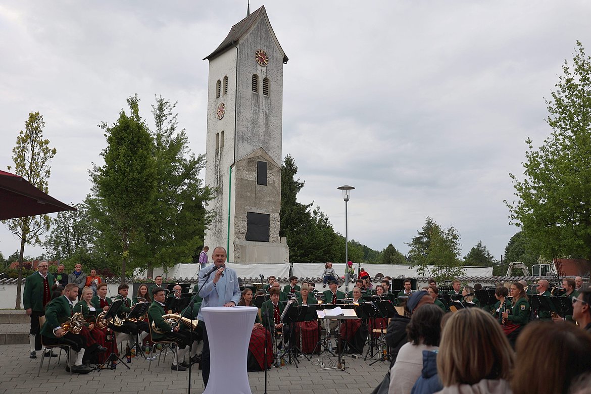 Ein MAnn spricht vor vielen Menschen. Die Musikkapelle Schwarzenbach sitzt hinter ihm
