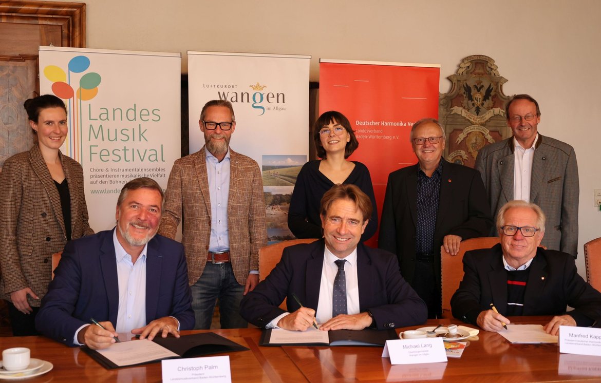 Acht Personen bei der Vertragsunterzeichnung 