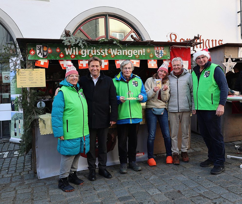 Eine Gruppe Menschen vor einem Marktstand.