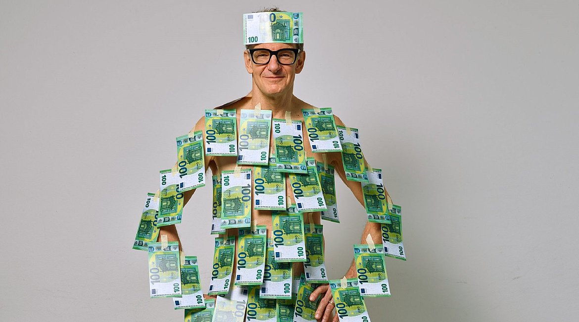 Ein Mann. Er hat lauter 100-Euro-Scheine an seinen Körper geklebt