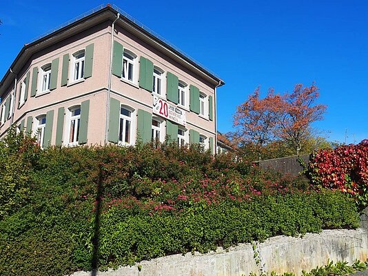 Jugendhaus von einem tiefen Sichtpunkt mit Hecke im Vordergrund