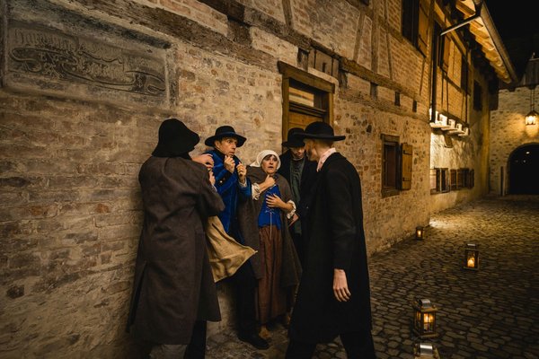 Drei Männer spielen den Überfall auf eine Frau und einen Mann