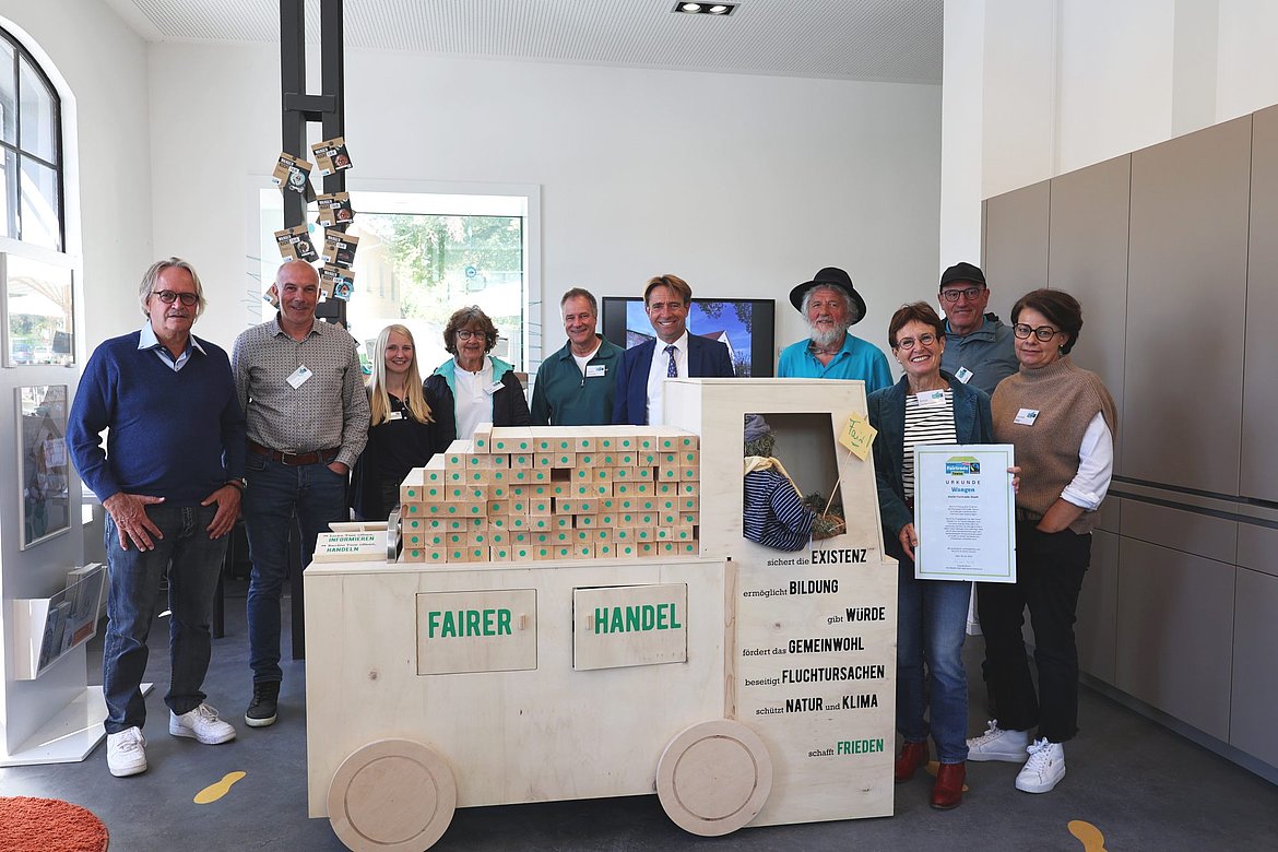 Zehn Personen zeigen einen Lkw aus Holz
