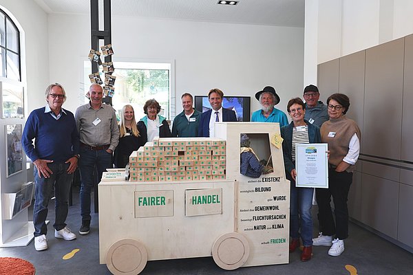 Zehn Personen zeigen einen Lkw aus Holz