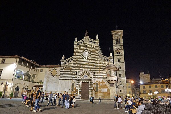 Nächtliche beleuchtete und belebte Straßenszene in Prato, im Hintergrund der dom
