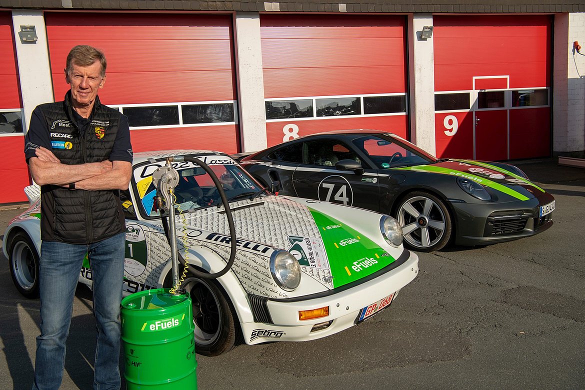 Ein Mann steht vor zwei Porsche Oldtimern.