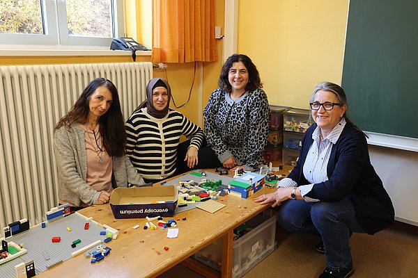 Frauen an einem Spieltisch für Kinder.