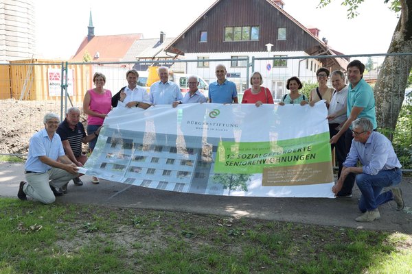 Menschen halten ein Bauzaunbanner mit dem Bild des Gebäudes